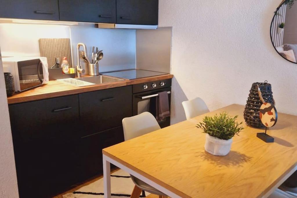 eine Küche mit einem Holztisch und eine Küche mit einer Spüle und einem Herd in der Unterkunft Studio au cœur des Alpes et Parking gratuit in Crans-Montana