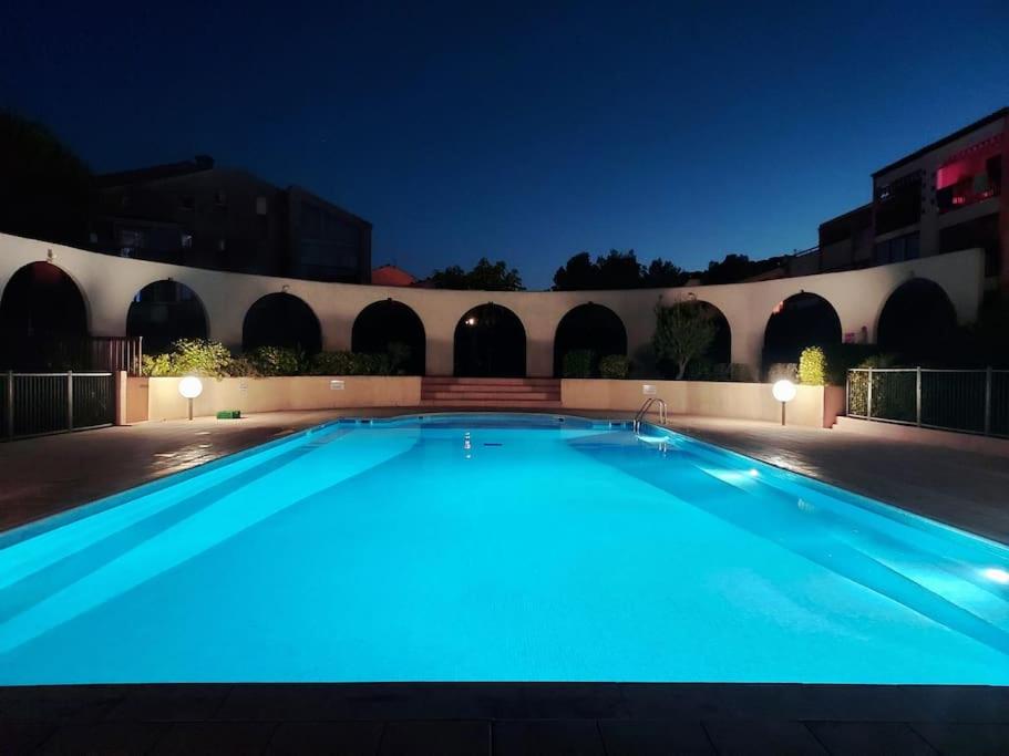 ein großer, nachts beleuchteter Pool in der Unterkunft Studio Mezzanine Piscine presqu'île de Giens in Hyères