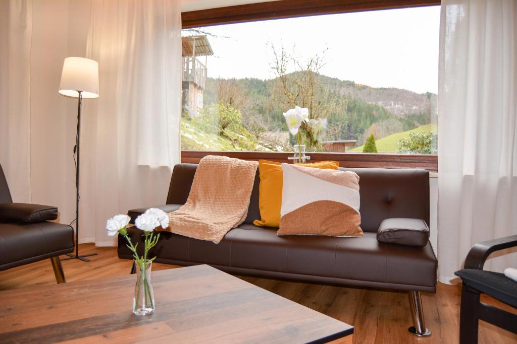 ein Wohnzimmer mit einem Sofa und einem großen Fenster in der Unterkunft Ferienwohnung Sonnenglück in Bad Peterstal-Griesbach