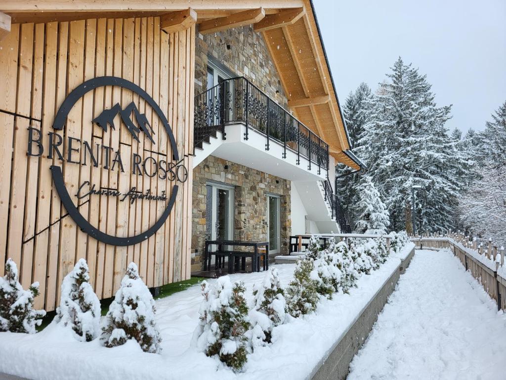 Ein Gebäude mit einem Schild im Schnee. in der Unterkunft Brenta Rosso - Charme Apartments in Fai della Paganella