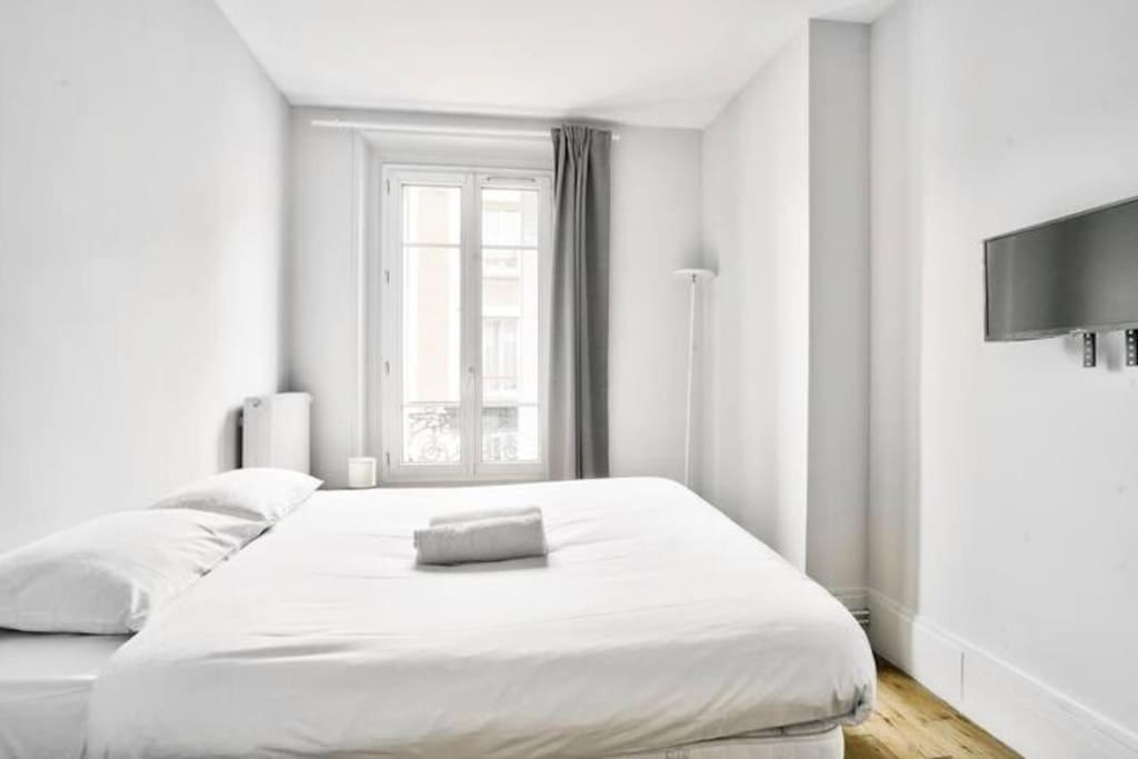 ein weißes Schlafzimmer mit einem großen Bett und einem Fenster in der Unterkunft Charmant T2 à 5 minute de Paris in Issy-les-Moulineaux