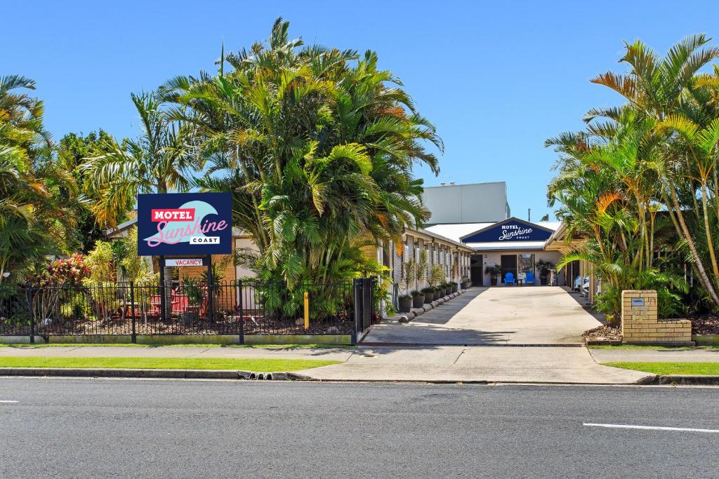 a street with palm trees in front of a store at Motel Sunshine Coast in Caloundra