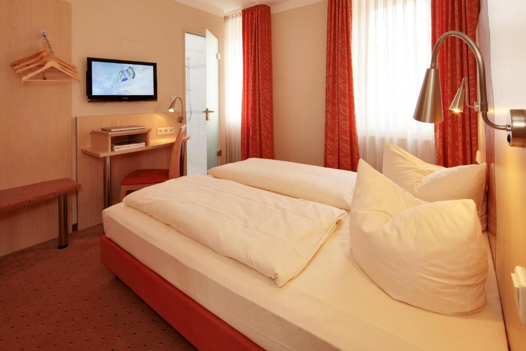 エッセンにあるHotel Petul An der Zecheのベッド2台とテレビが備わるホテルルームです。