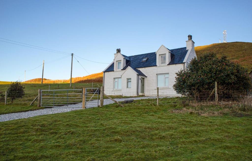 una casa blanca en un campo con una valla en 2 South Duntulm, en Kilmaluag