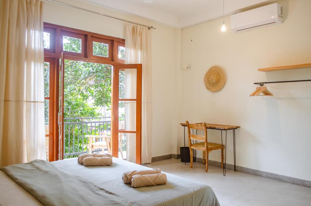 a bedroom with a bed and a table and a window at The Native Weligama in Weligama