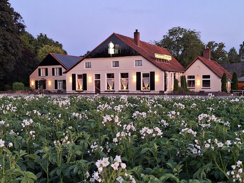 a large white house with a field of flowers at Hotel de Lindeboom in Winterswijk