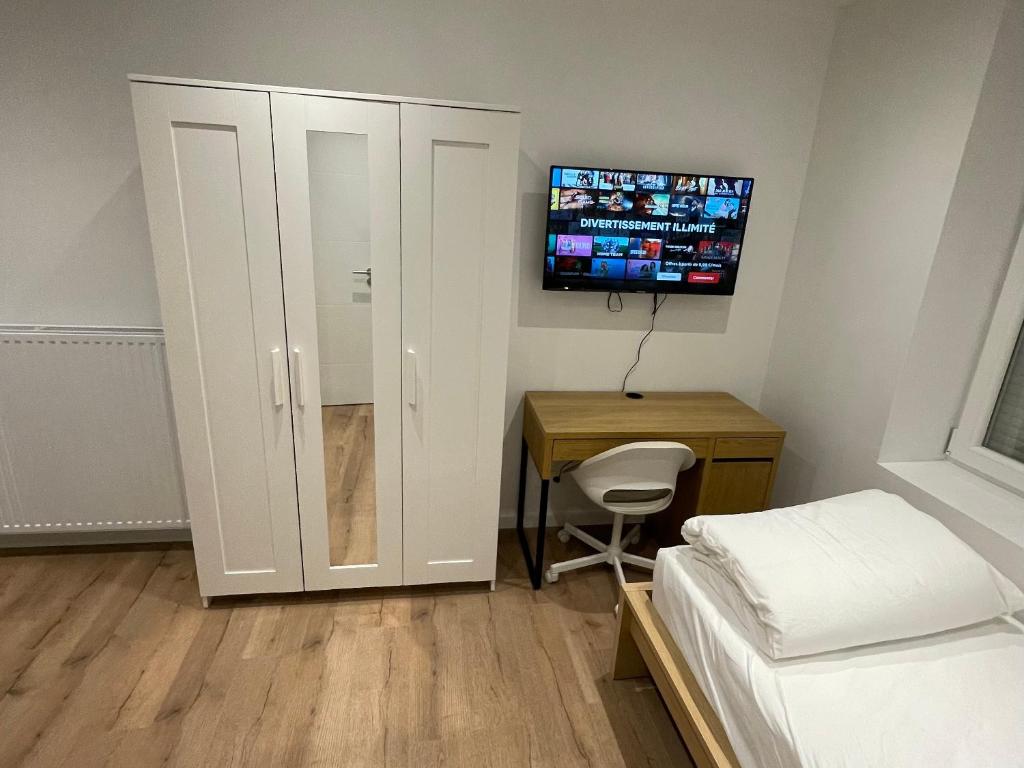 ein Schlafzimmer mit einem Bett, einem Schrank und einem Schreibtisch in der Unterkunft Studio meublé Longwy-Haut Centre in Longwy