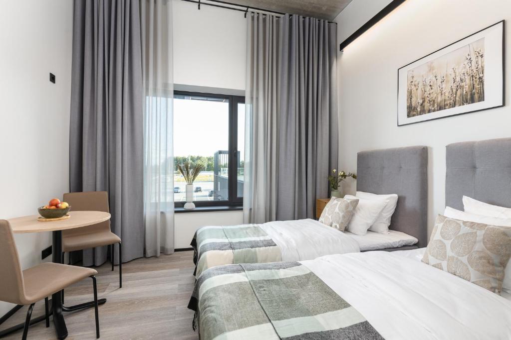 um quarto de hotel com duas camas e uma mesa e uma secretária em Väo Keskus Modern Guest Apartments em Talin