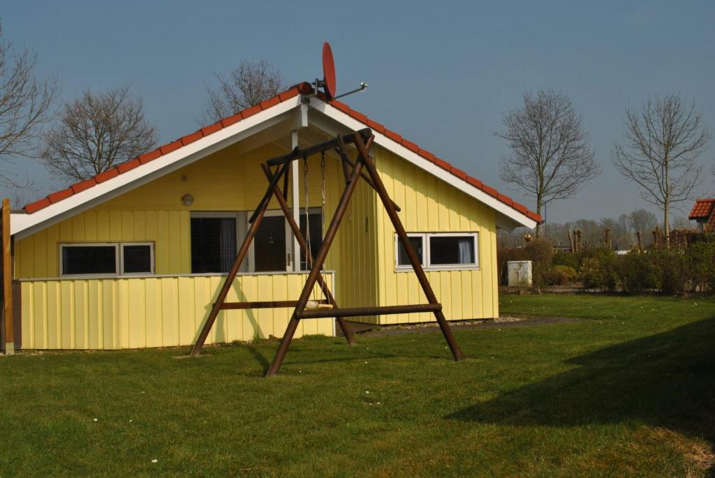 eine Schaukel vor einem gelben Gebäude in der Unterkunft Ferienhaus Korsör in Otterndorf