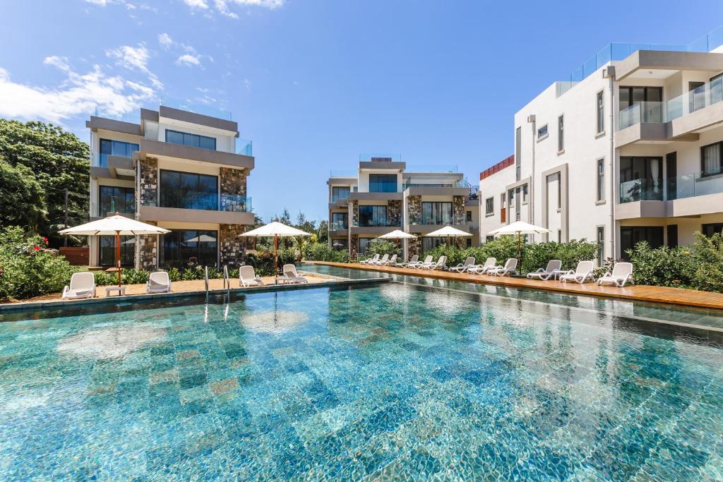 a swimming pool with chairs and umbrellas in front of buildings at Brand new, Beachfront Ocean Terraces, Poste Lafayette-Apt-C2 in Poste Lafayette