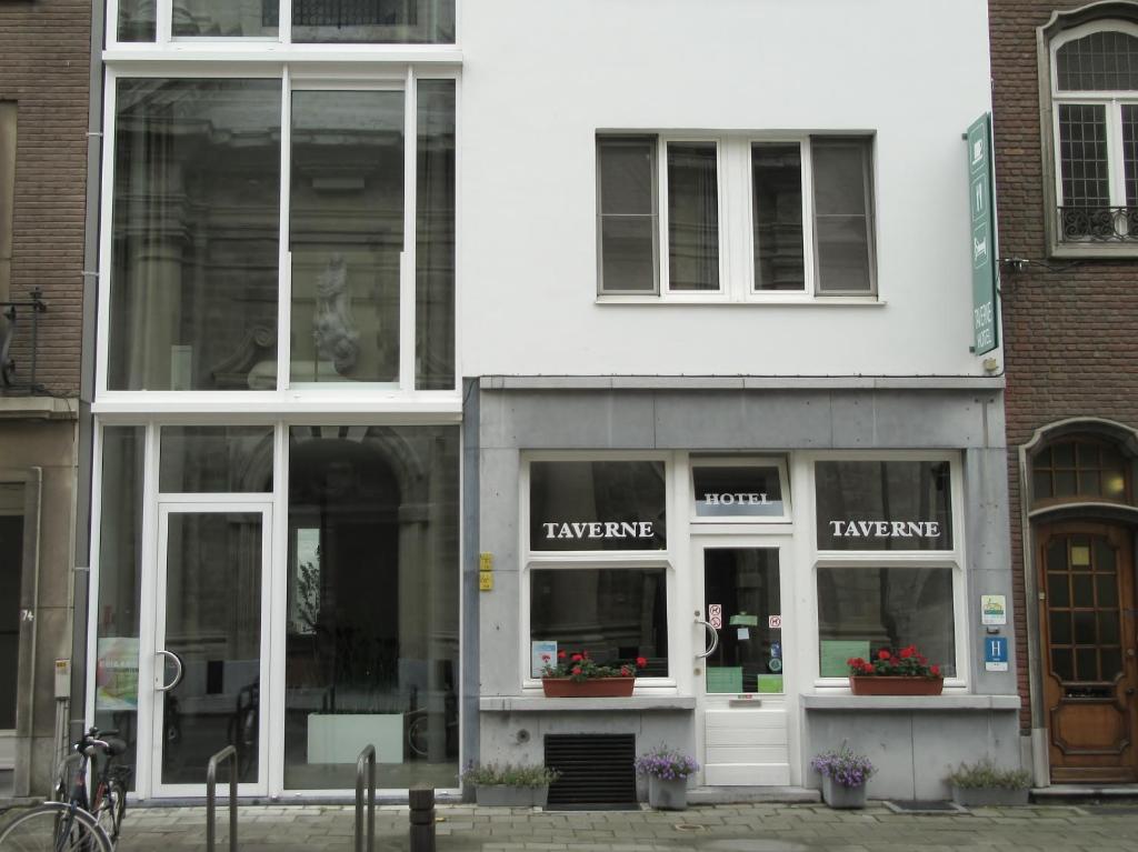 duży biały budynek ze szklanymi oknami wychodzącymi na ulicę w obiekcie Hotel Muske Pitter w mieście Mechelen