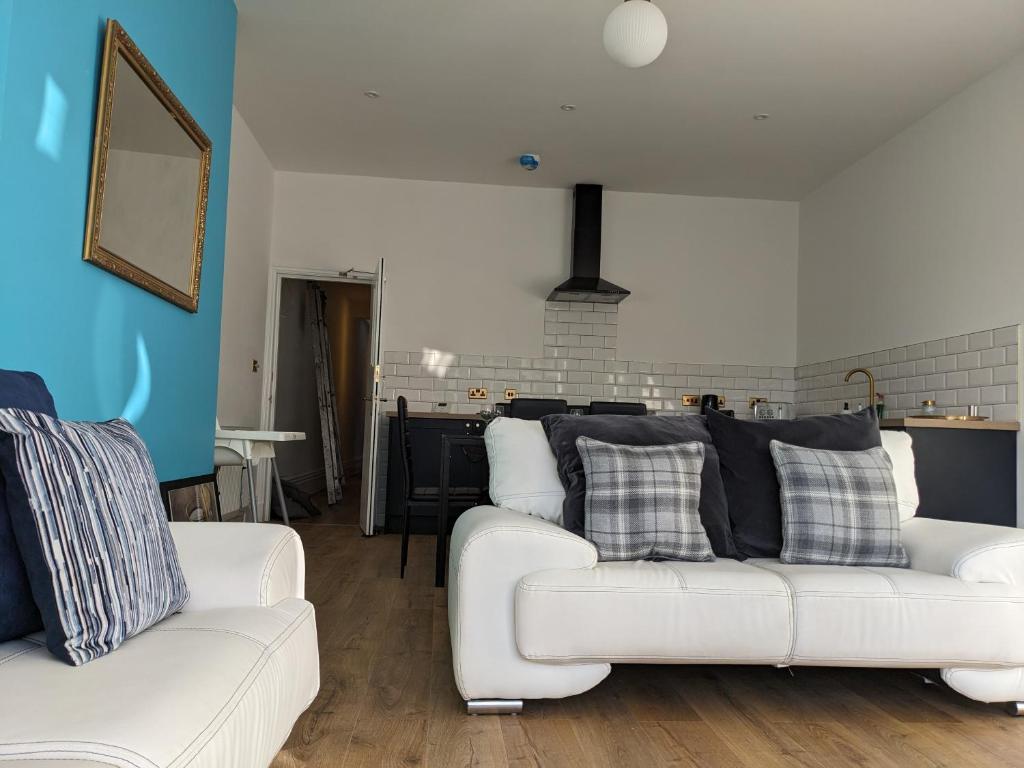 een woonkamer met 2 witte banken en een keuken bij Dolce Central Lord St. Flat 2 in Southport