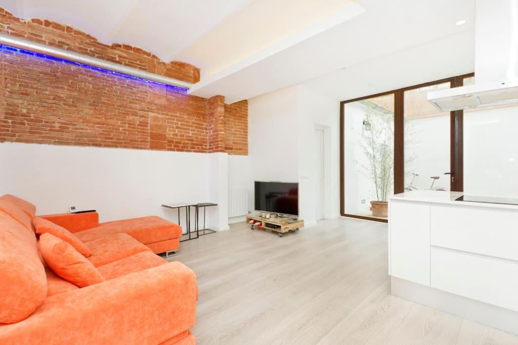 a living room with an orange couch and a brick wall at Roós, design loft near the sea. in Barcelona