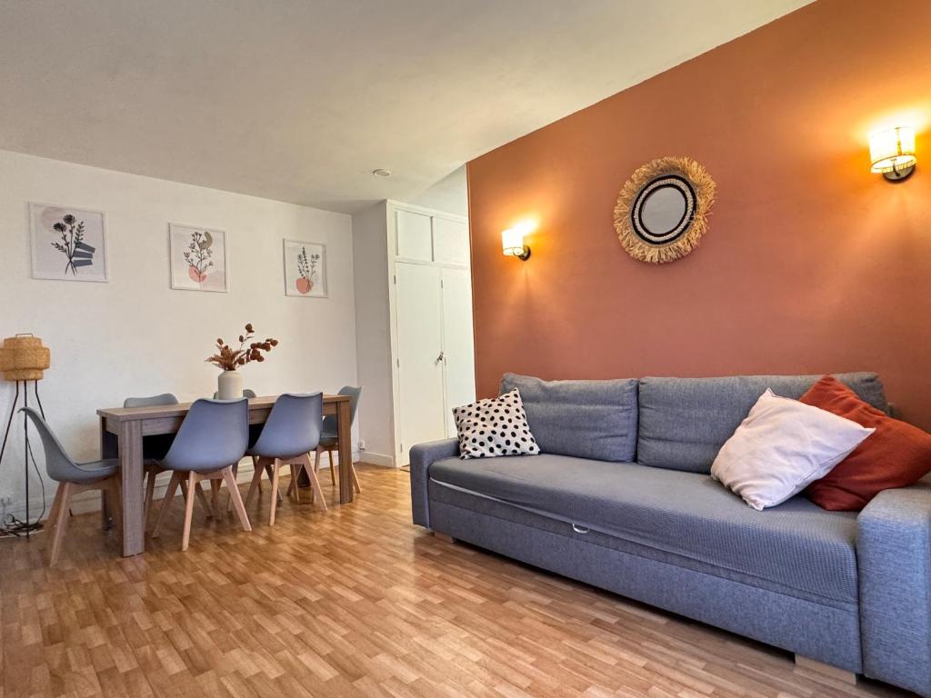 a living room with a blue couch and a table at Appartement F3 15 mins à Paris in Aubervilliers