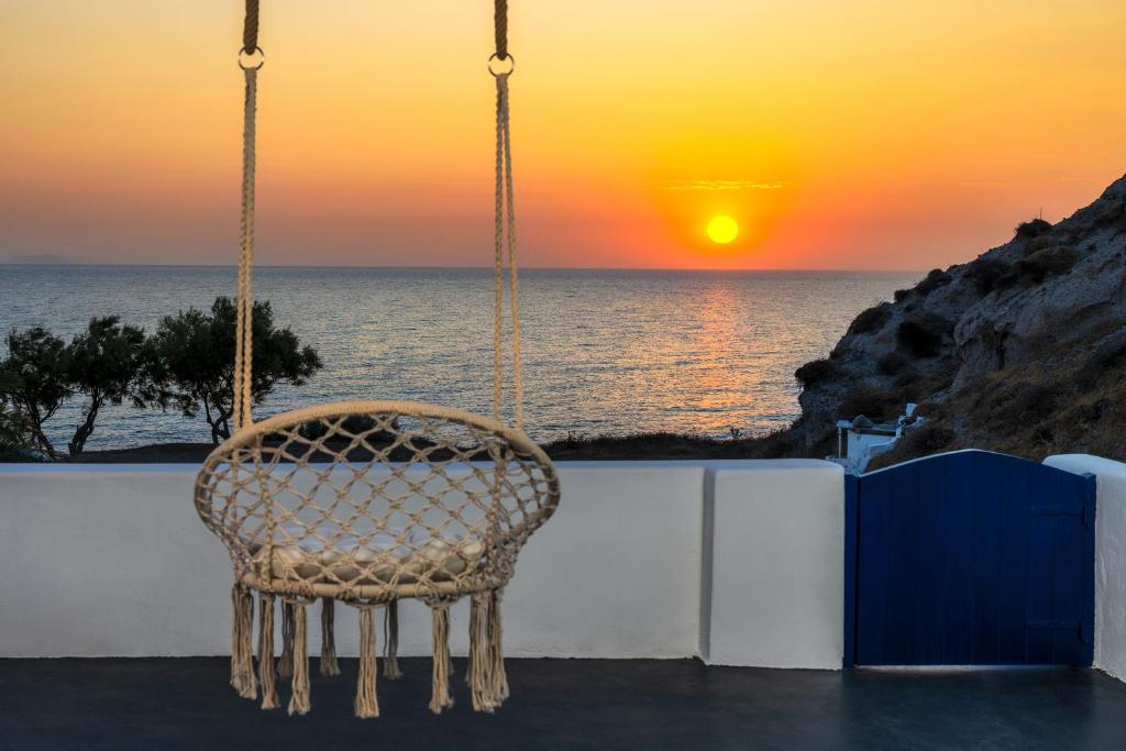een rotan stoel zittend op een veranda kijkend naar de zonsondergang bij Sonus Mare Beach Apartments, Vourvoulos Beach in Vourvoúlos