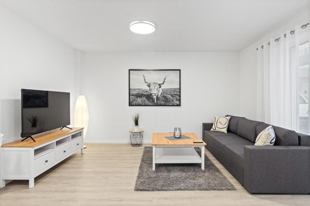 een woonkamer met een bank en een tv bij WINETIME - modern - Boxspringbetten - Netflix - Nähe Mercedes-Benz in Wörth am Rhein
