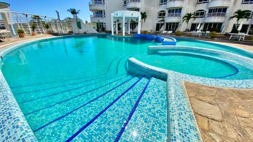 a swimming pool with blue water in front of a building at Alquiler de Apartamento vacacional en la Isla de Margarita in Pampatar