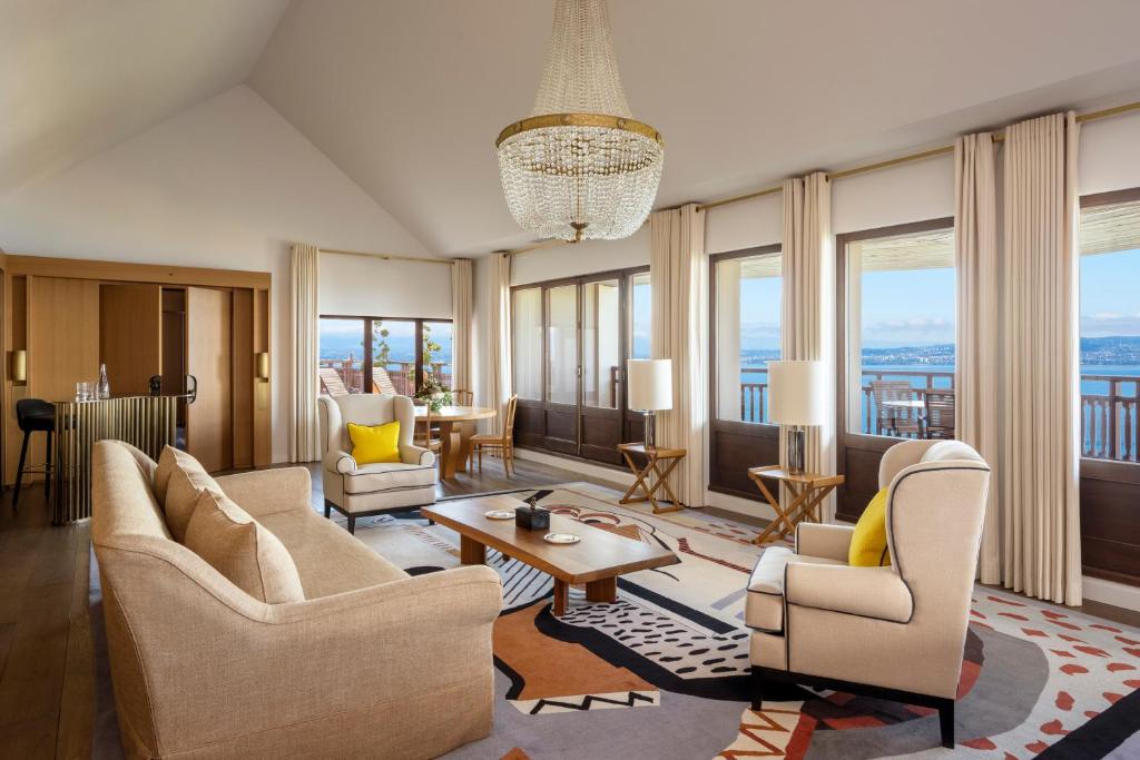 a living room with chairs and tables and windows at Hôtel Royal in Évian-les-Bains