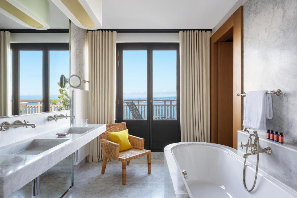 a bathroom with two sinks and a tub with a window at Hôtel Royal in Évian-les-Bains