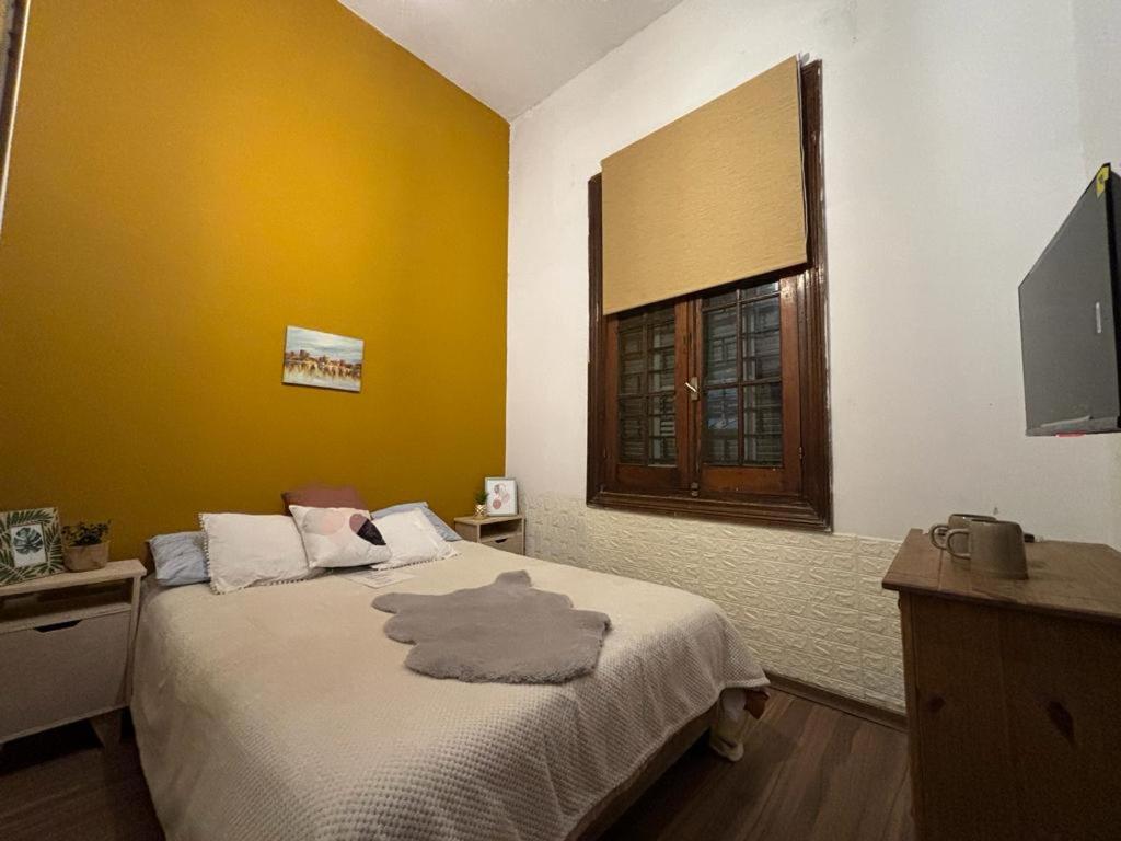 um quarto com uma cama com uma parede amarela e uma janela em Expreso terminal em Montevidéu