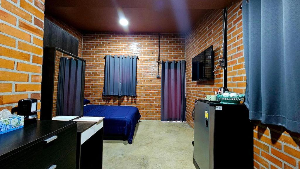 una camera con un letto blu e un muro di mattoni di บ้านสวนลุงแจน ฟิชชิ่งพาร์ค แอนด์ รีสอร์ท 
