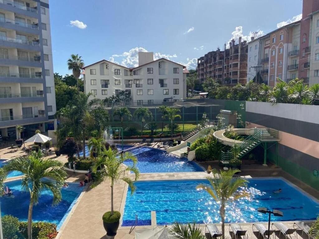 熱河市的住宿－Apartamentos em Rio Quente com maravilhosa área de lazer e linda vista，一座棕榈树和建筑的大型游泳池