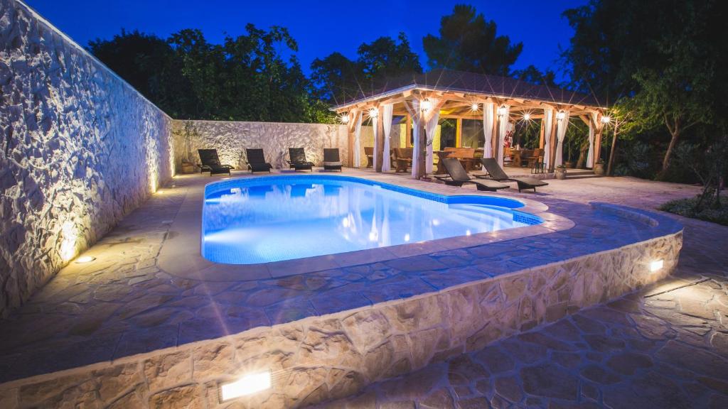 a swimming pool in a backyard at night at Apartments Simona in Lopar