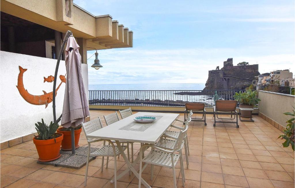 a patio with a table and chairs and an umbrella at Stunning Apartment In Aci Castello With Kitchen in Aci Castello
