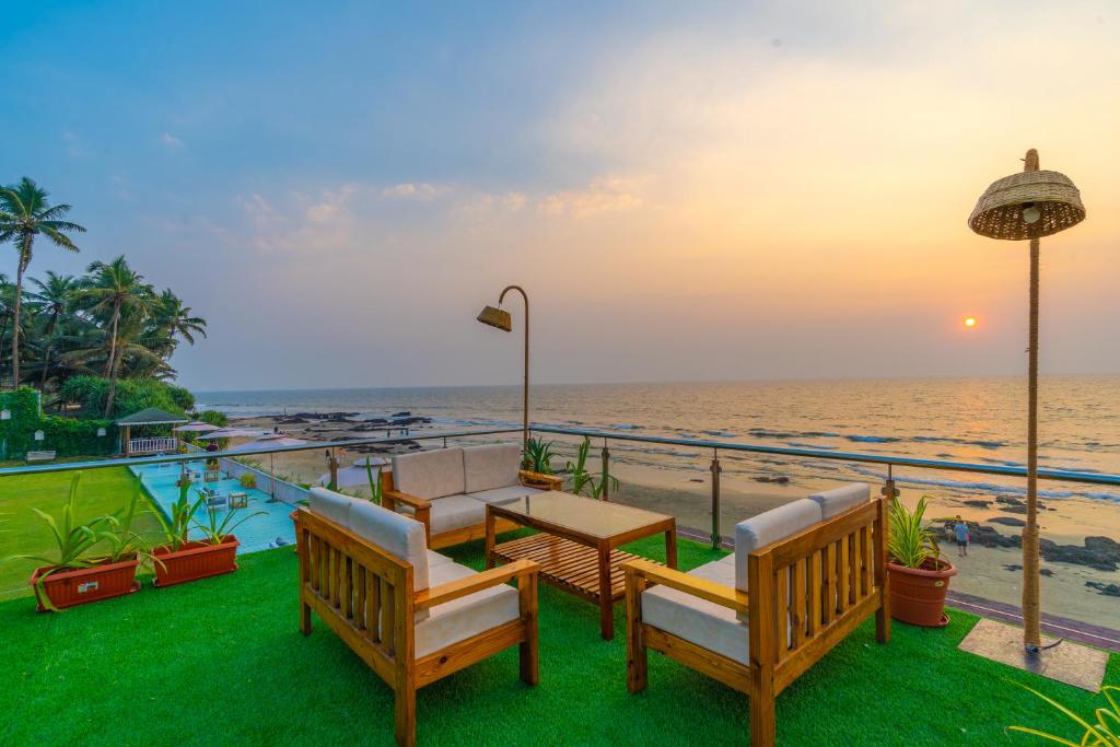 balcón con mesa y sillas y la playa en La Cabana Beach & Spa, By Ashvem Beach, en Mandrem