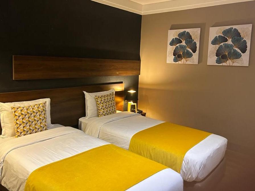 two beds in a hotel room with yellow and white sheets at Yto boutique Hotel in Casablanca