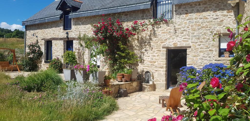 ein Steingebäude mit Blumen davor in der Unterkunft Gîte de charme en pleine nature in Saint-Jean-la-Poterie