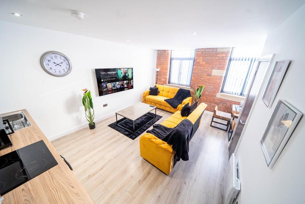 a living room with a yellow couch and a brick wall at Fancy 2-Bedroom Apartment with 2 Bathrooms in Bradford Town Centre in Bradford