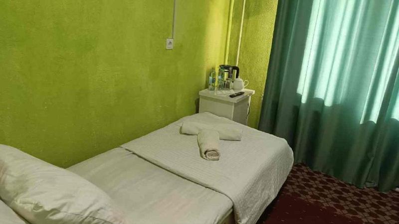 a small bed in a room with green walls at DAVR хостел in Namangan