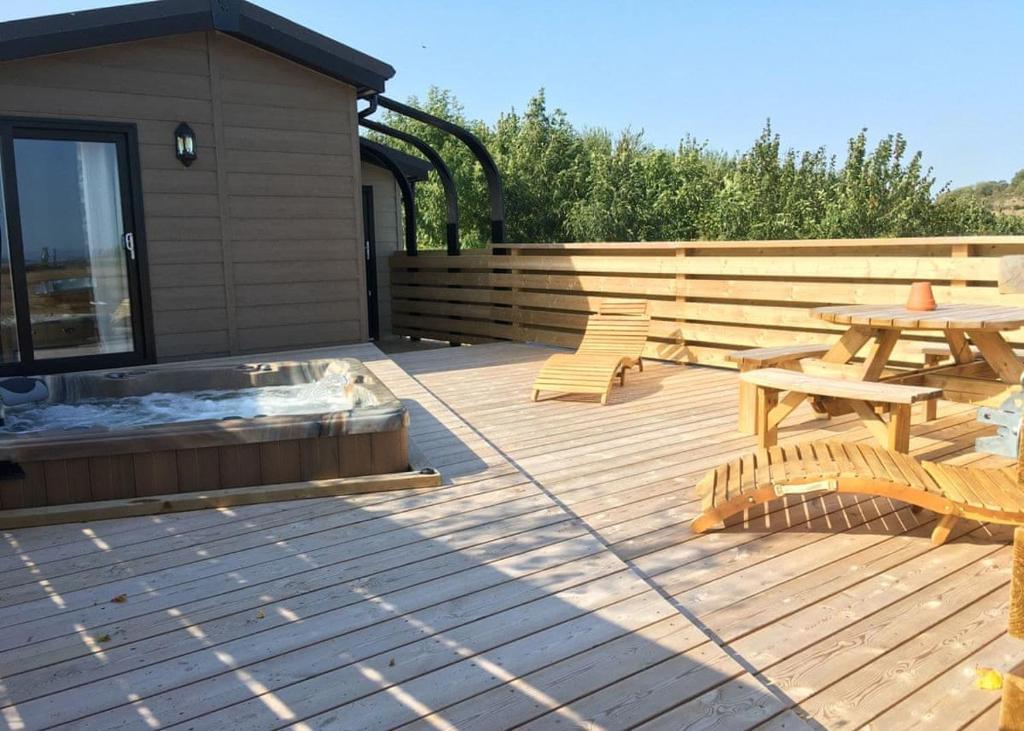 a wooden deck with a picnic table and a fire pit at Henfields Country Retreat in Otterhampton