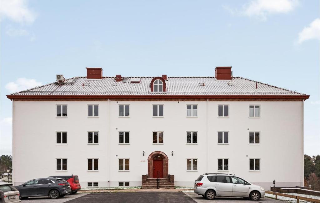 een groot wit gebouw met auto's geparkeerd op een parkeerplaats bij 3 Bedroom Gorgeous Apartment In Stjrnhov in Stjärnhov