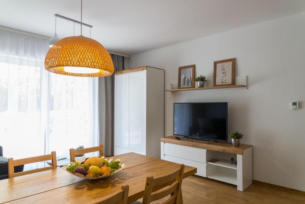 VacationClub - Spokojna 24A Apartament D1 في فيسلا: غرفة طعام مع طاولة مع وعاء من الفواكه