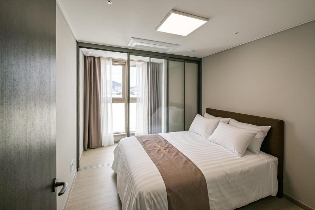 sypialnia z dużym łóżkiem i oknem w obiekcie Ocean Terrace Yeosu w mieście Yeosu