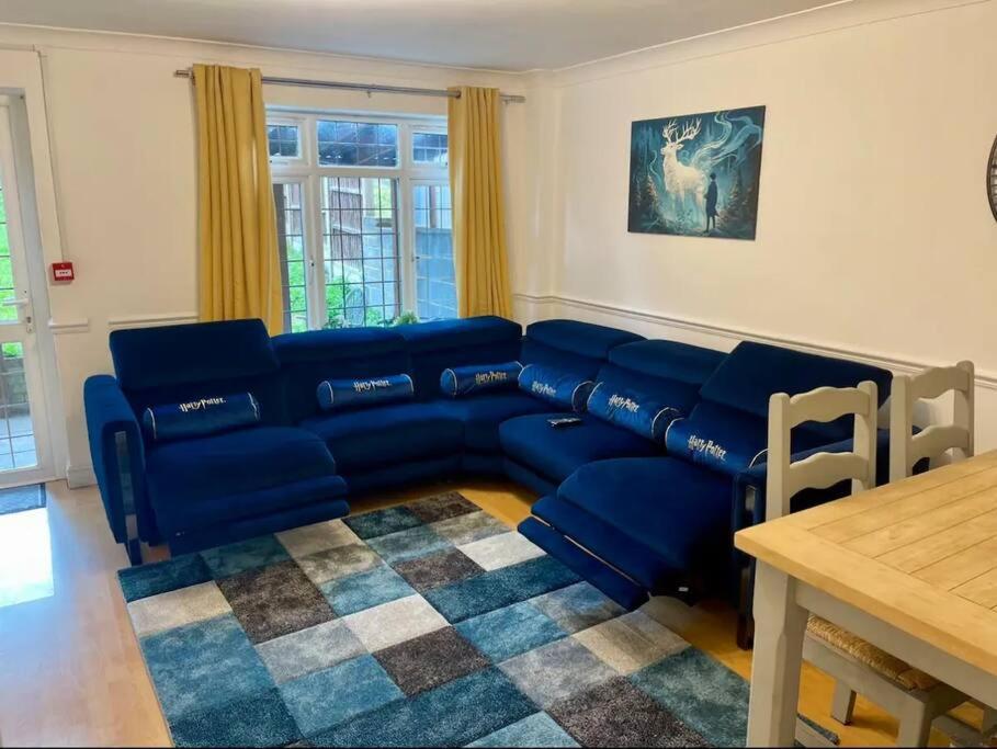 a living room with a blue couch and a table at Spacious 5 Bedroom House- Harry potter world & London in Watford