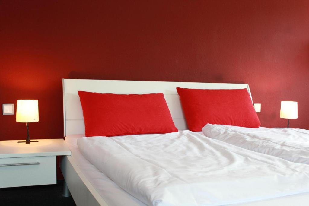 - une chambre avec 2 oreillers rouges sur un lit dans l'établissement Restaurant Ollex and beds Zimmer 2, à Bliesdorf