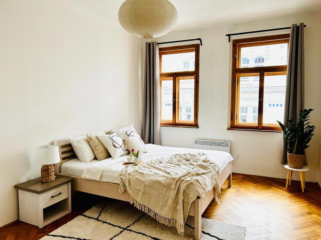 - une chambre blanche avec un lit et 2 fenêtres dans l'établissement Big family apartment, à Prague