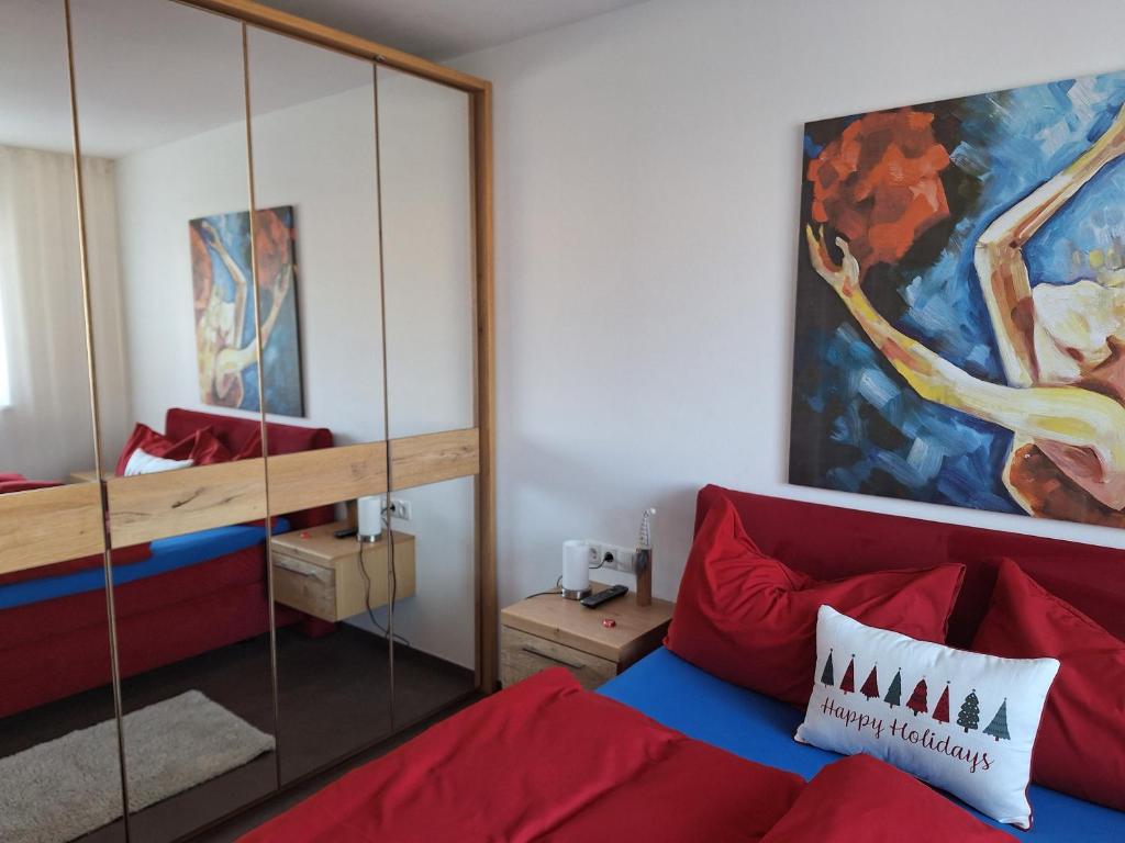 sala de estar con sofá rojo y espejo en FeelHome Bruneck, en Brunico