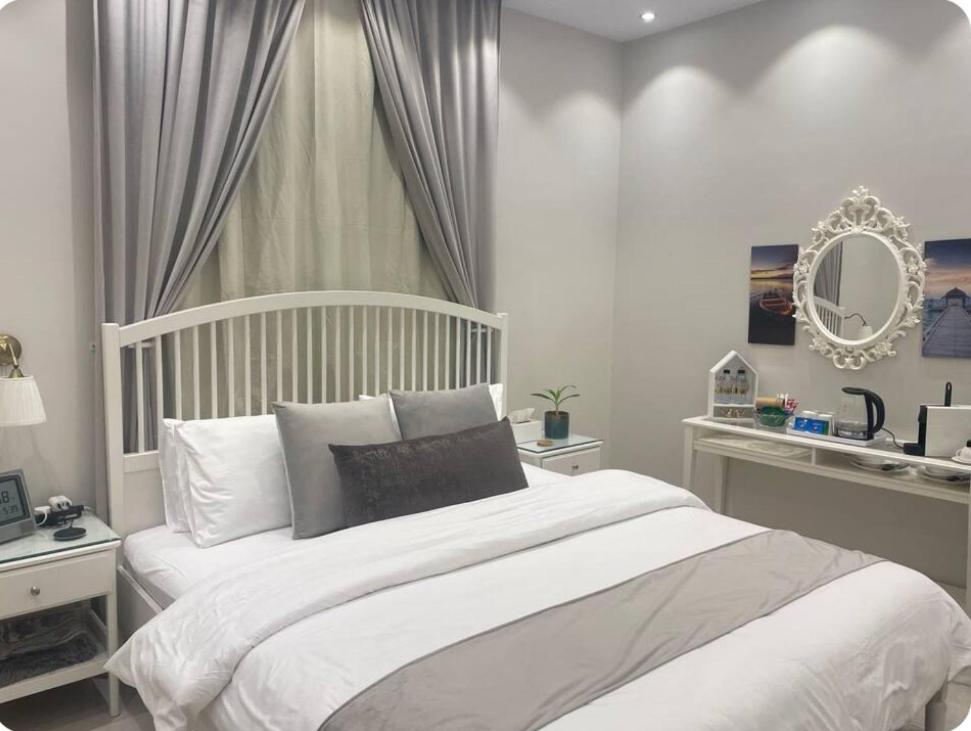 - une chambre avec un lit blanc et un miroir dans l'établissement Al Aseel Apartment Buyoot Al Diyafah, à Taif