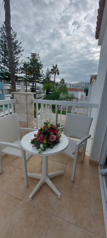 a white table and chairs on a balcony with flowers at New Famagusta Hotel & Suites in Ayia Napa