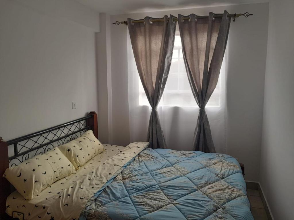 a bedroom with a bed and a window with curtains at REMA AIRBNB'S in Nairobi