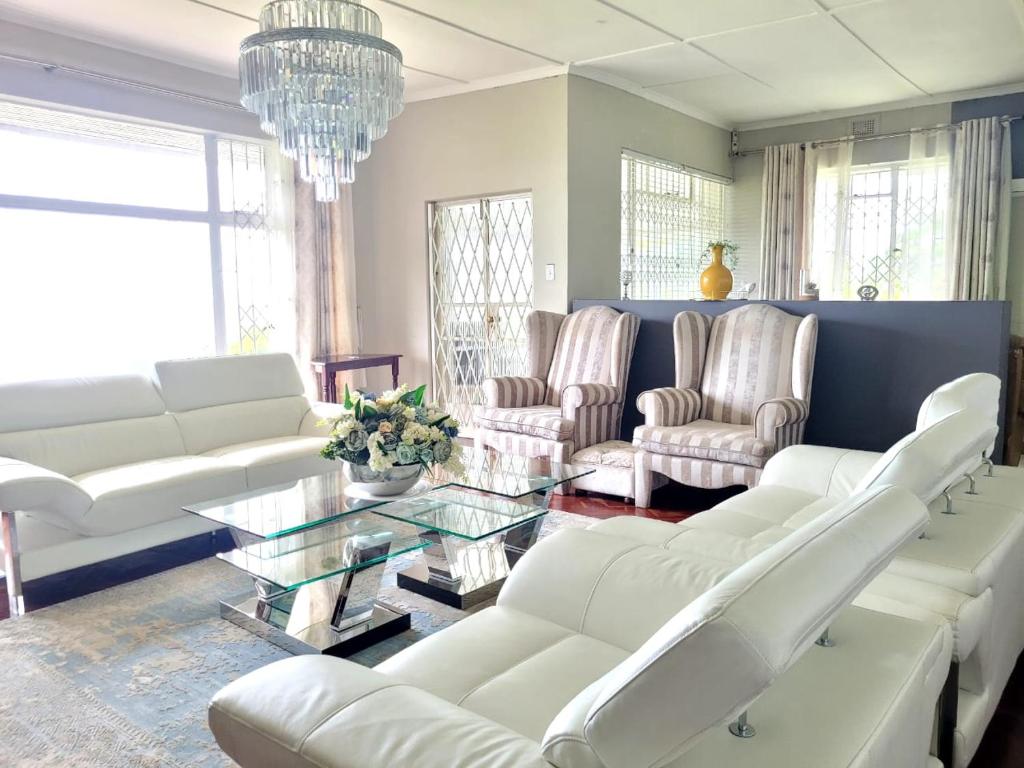 a living room with white furniture and a chandelier at City Gate Two in Pietermaritzburg