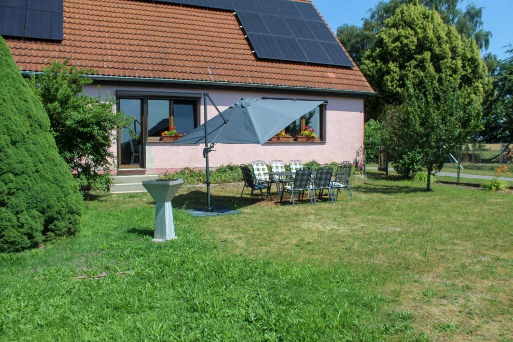 a house with a table and an umbrella in the yard at Ferienwohnung auf dem Alpaka-Hof in Rubkow