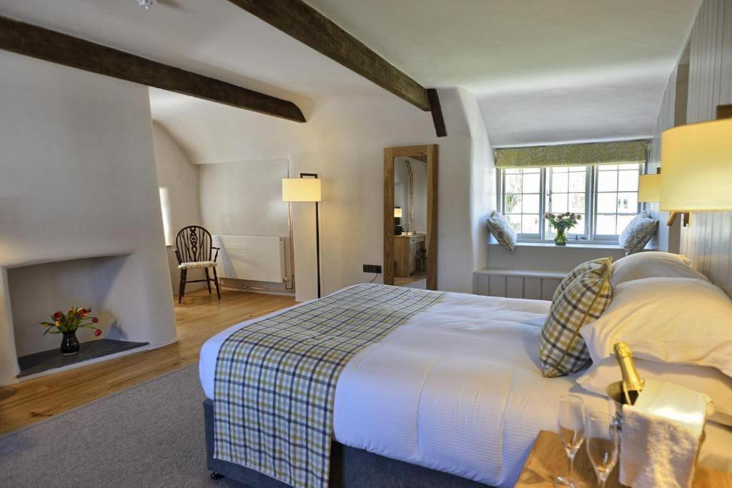 een slaapkamer met een groot bed en een open haard bij Ring of Bells in North Bovey