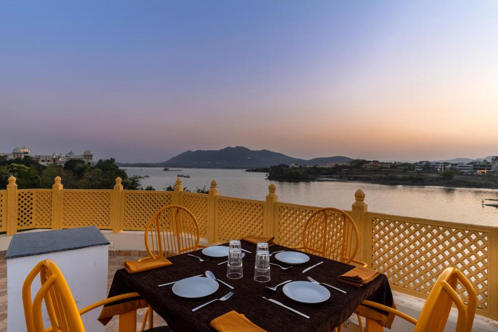 una mesa en un balcón con vistas al río en Atrangi Hotel & lakeview cafe at PICHOLA LAKE by JD, en Udaipur