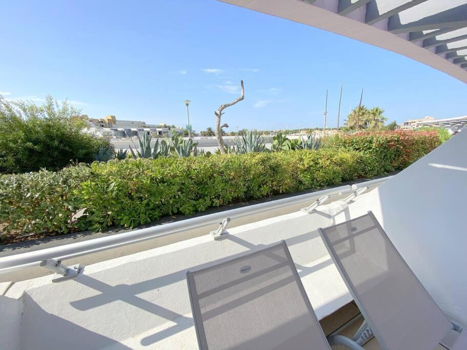 un ordinateur portable assis sur un balcon avec une haie dans l'établissement Appartement 114, Port Ambonne au village naturiste, au Cap d'Agde