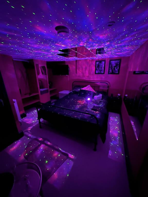 una camera da letto viola con un letto illuminato di The Indulging Basement a Barnsley